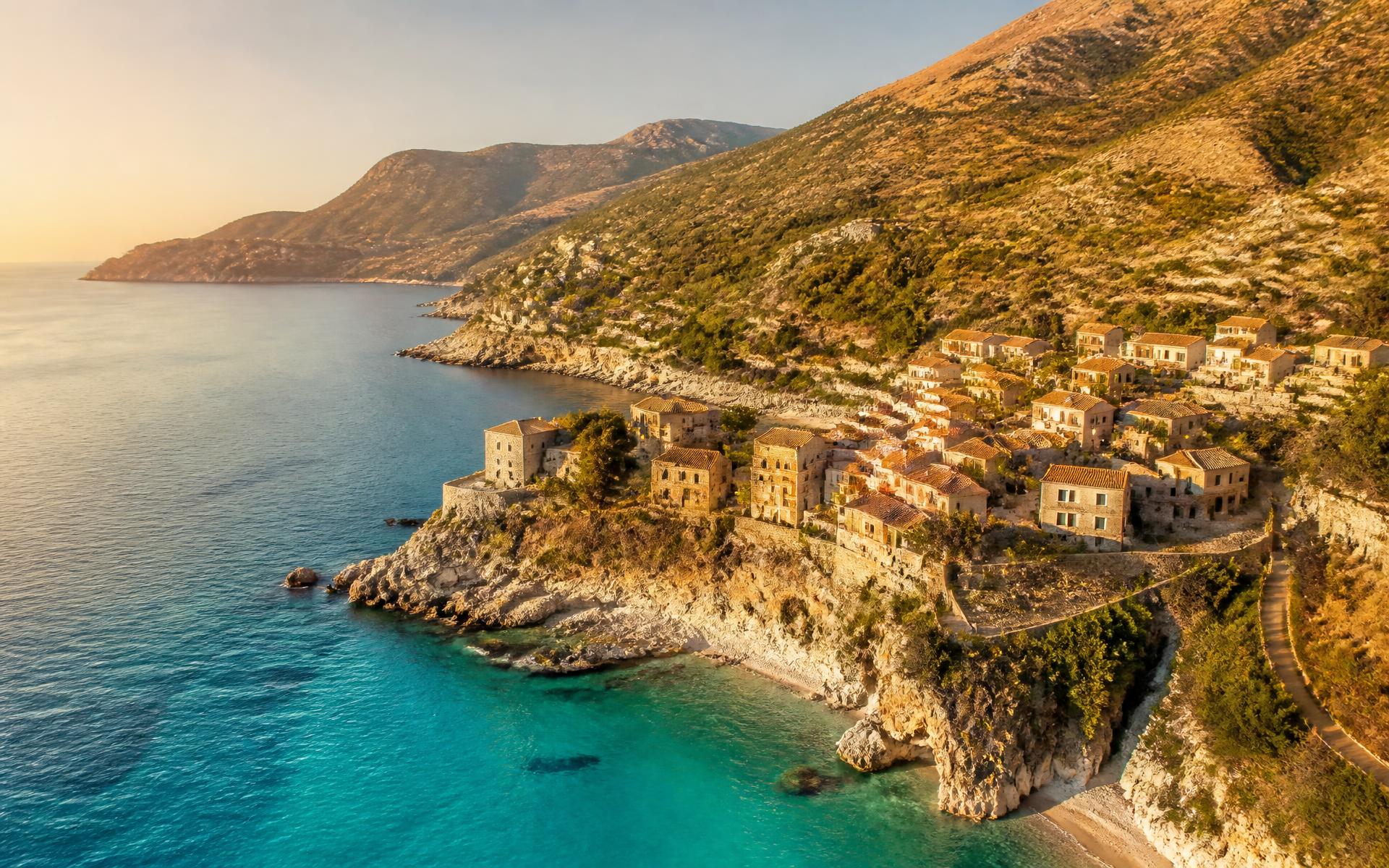 Golden-hour view of a stone village on the Albanian Riviera coastline